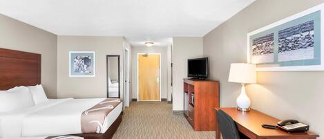 A hotel room with a bed, a desk, a television, and a lamp.