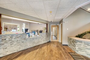 Una zona de recepción con mostrador de piedra, una computadora y un pasillo que conduce a otra habitación.