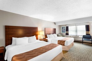 A hotel room with two beds, a nightstand, a chair, a lamp, and a large window with curtains. - Quality Inn & Suites Gorham Riverside (Gorham)