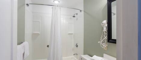 Un baño con bañera, inodoro y lavamanos, que incluye una cortina de ducha y un espejo.