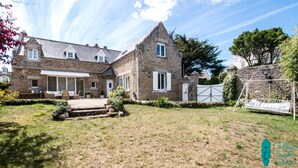A stone house with a patio, a swing, and a gated area. - Cottage Santa Teresa (Saint-Lunaire)