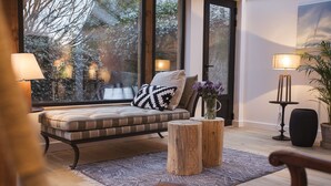 A cozy seating area with a cushioned bench, a wooden coffee table, and a lamp. - Cottage Santa Teresa (Saint-Lunaire)