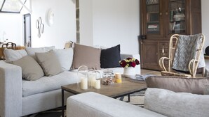 A living room with a sofa, a coffee table with candles and a vase, and a wicker chair. - Cottage Santa Teresa (Saint-Lunaire)
