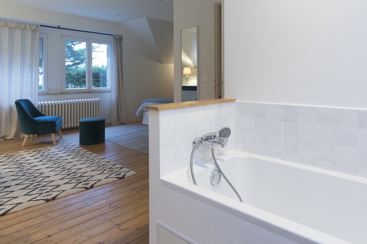 Een moderne badkamer met een bad, een stoel en een raam met gordijnen.