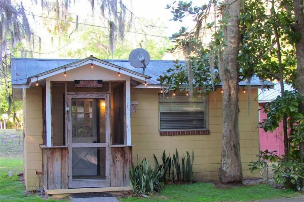 A small, single-story building with a porch, a satellite dish, and a window with shutters.