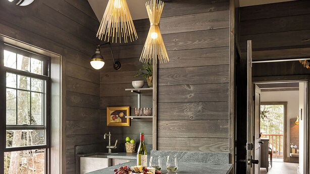 A kitchen with a central island, wooden stools, pendant lighting, and a view through a window. - Hidden Pond (Kennebunkport)