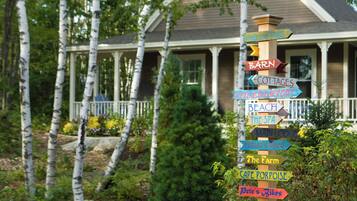 A wooden signpost with multiple directional signs pointing to various local attractions such as a nature trail, barn, cottages, beach, spa, main lodge, artist's shed, the farm, cafe porpoise, and bikes.
