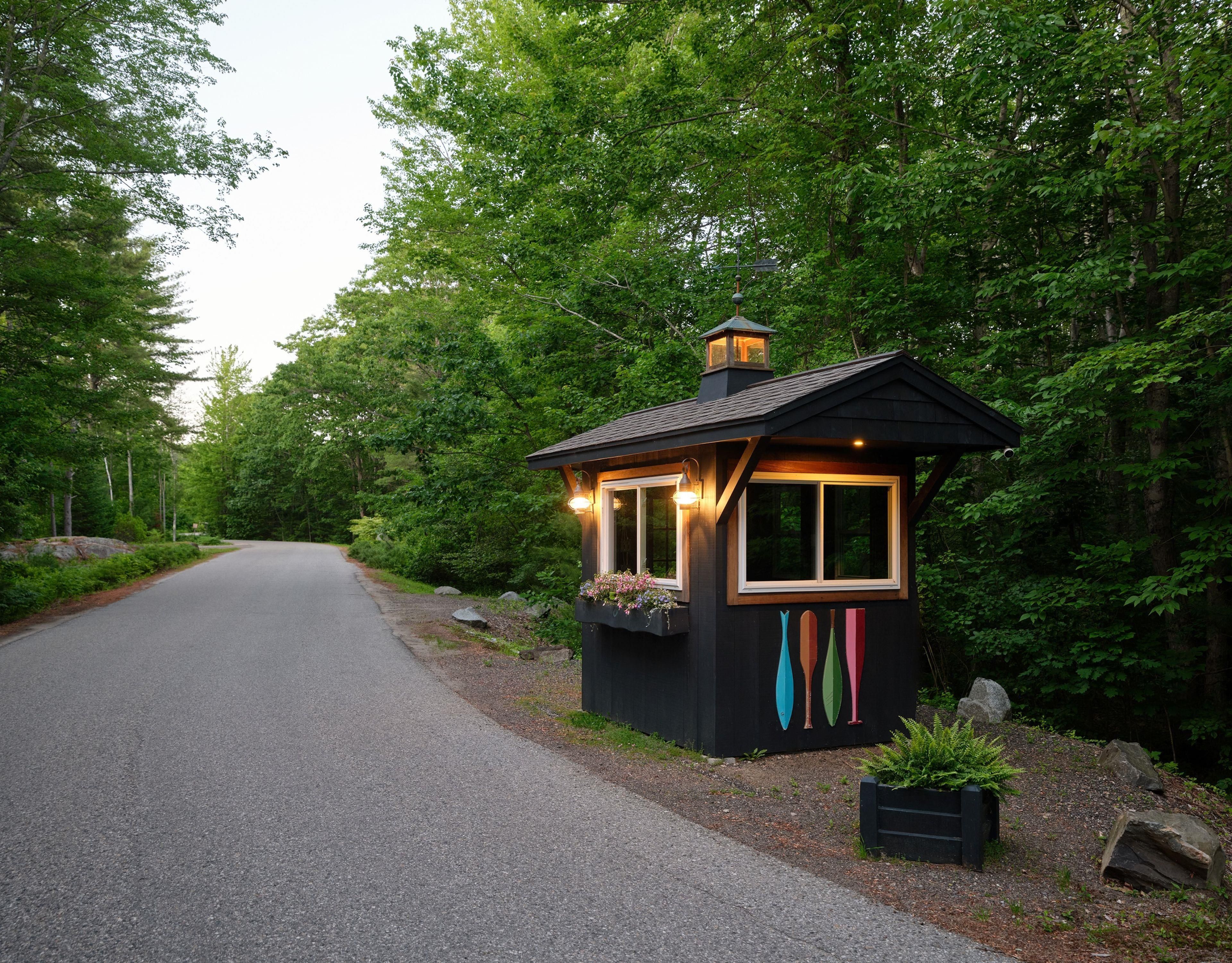 A small wooden cabin with a porch, surrounded by dense forest.