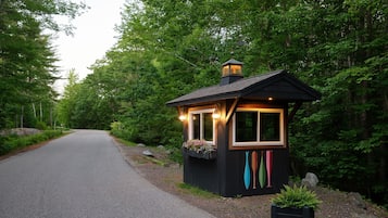 A small wooden cabin with a porch, surrounded by dense forest.