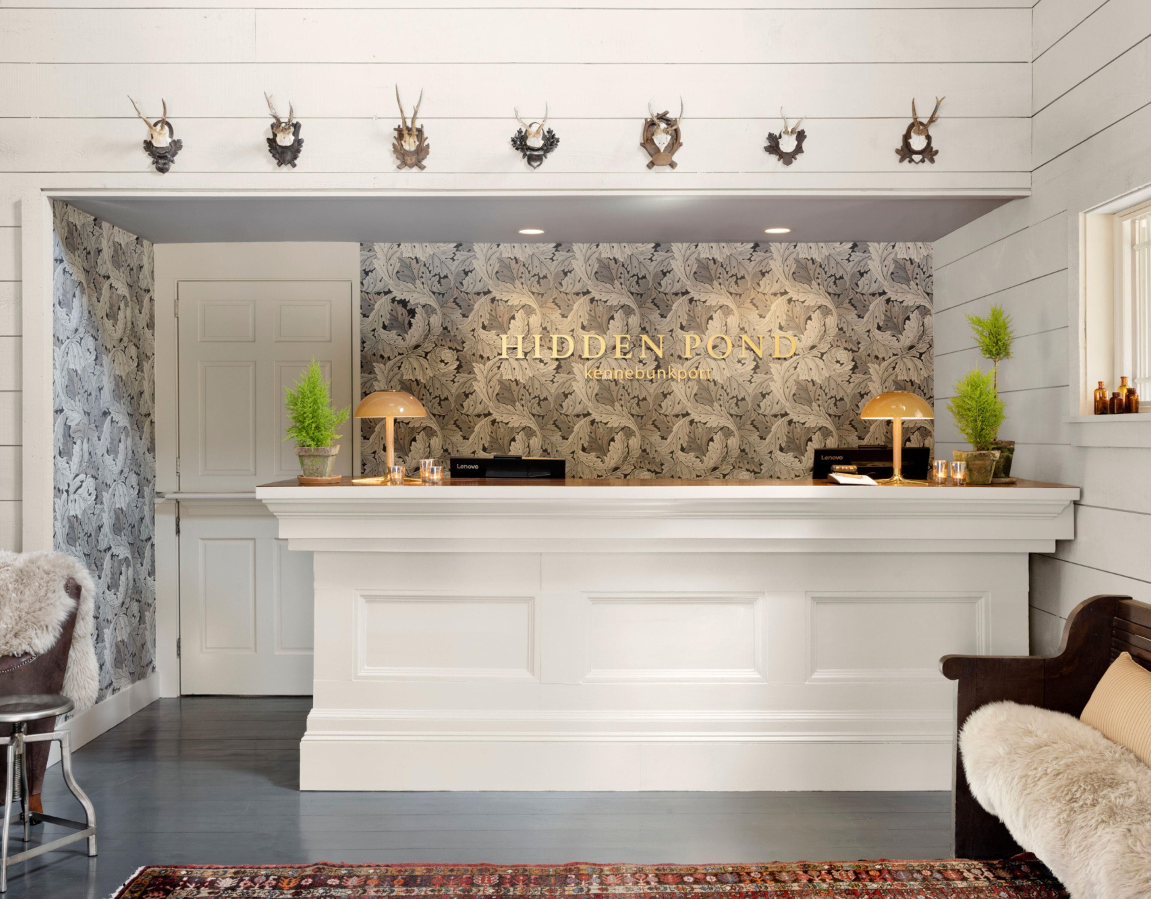 A modern reception desk with a marble-patterned wall, a white counter, and decorative antler wall art.