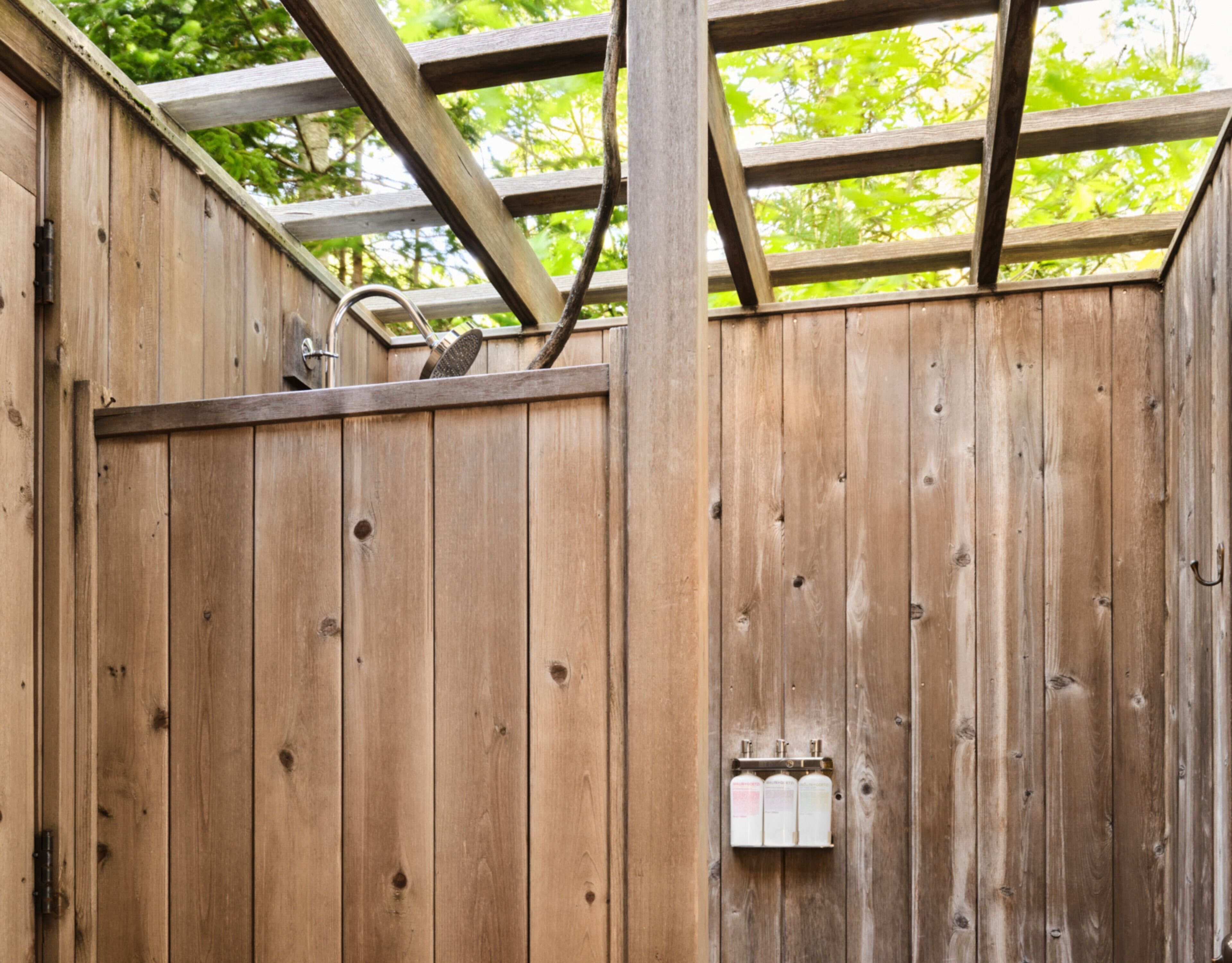 A wooden fence with a metal gate and a small electrical box attached to it.