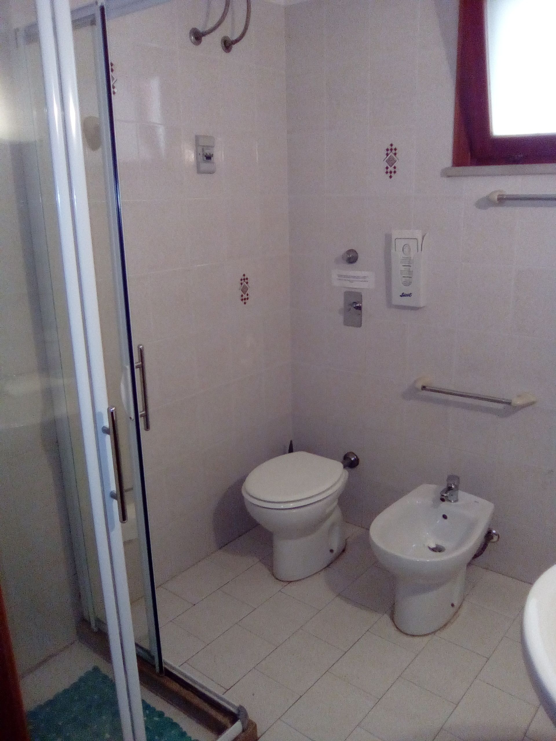 Ein Badezimmer mit Toilette, Bidet und einer Duschkabine aus Glas.