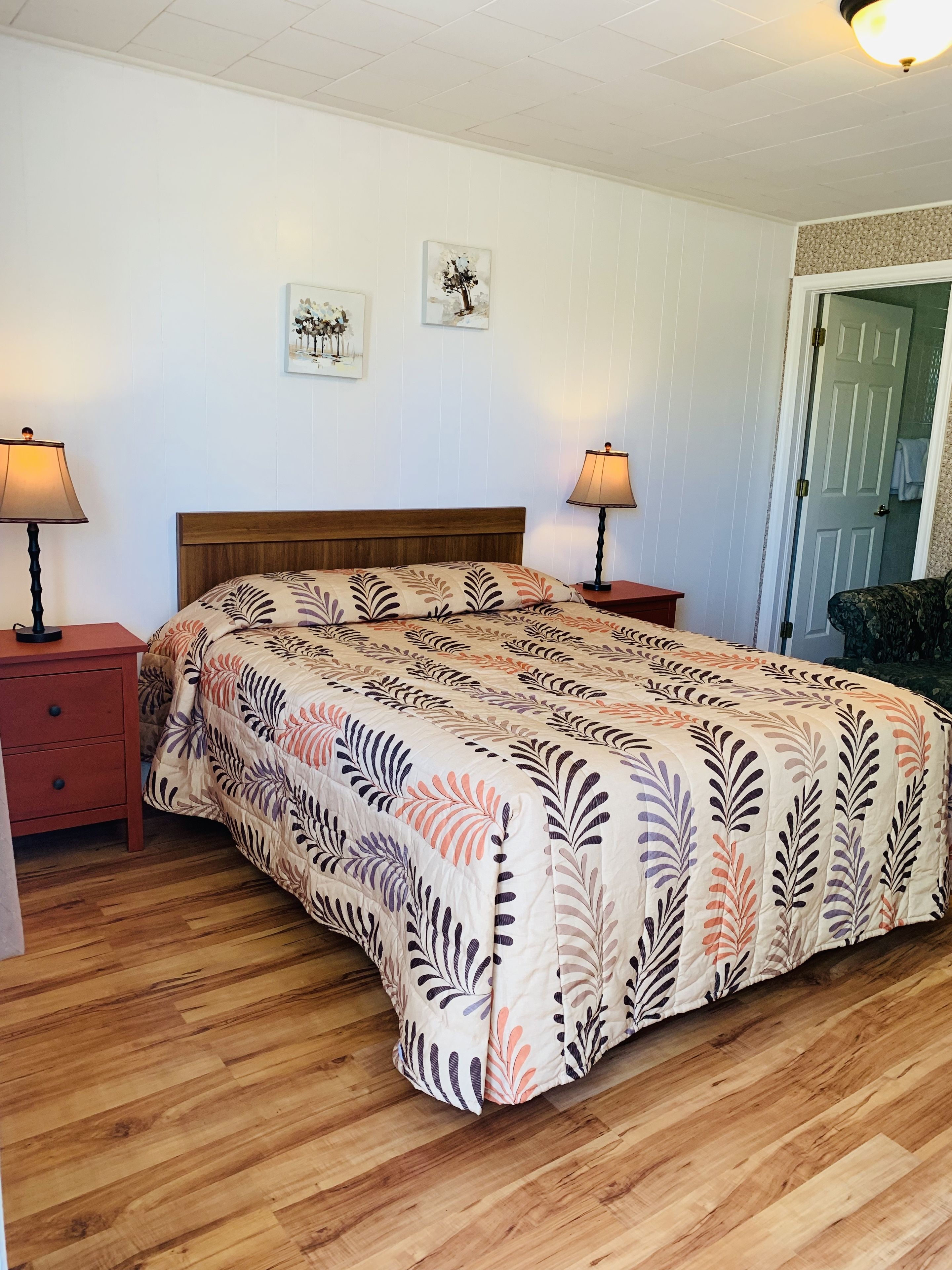 Une chambre à coucher avec un lit en bois, deux tables de chevet et une porte sur le côté droit.