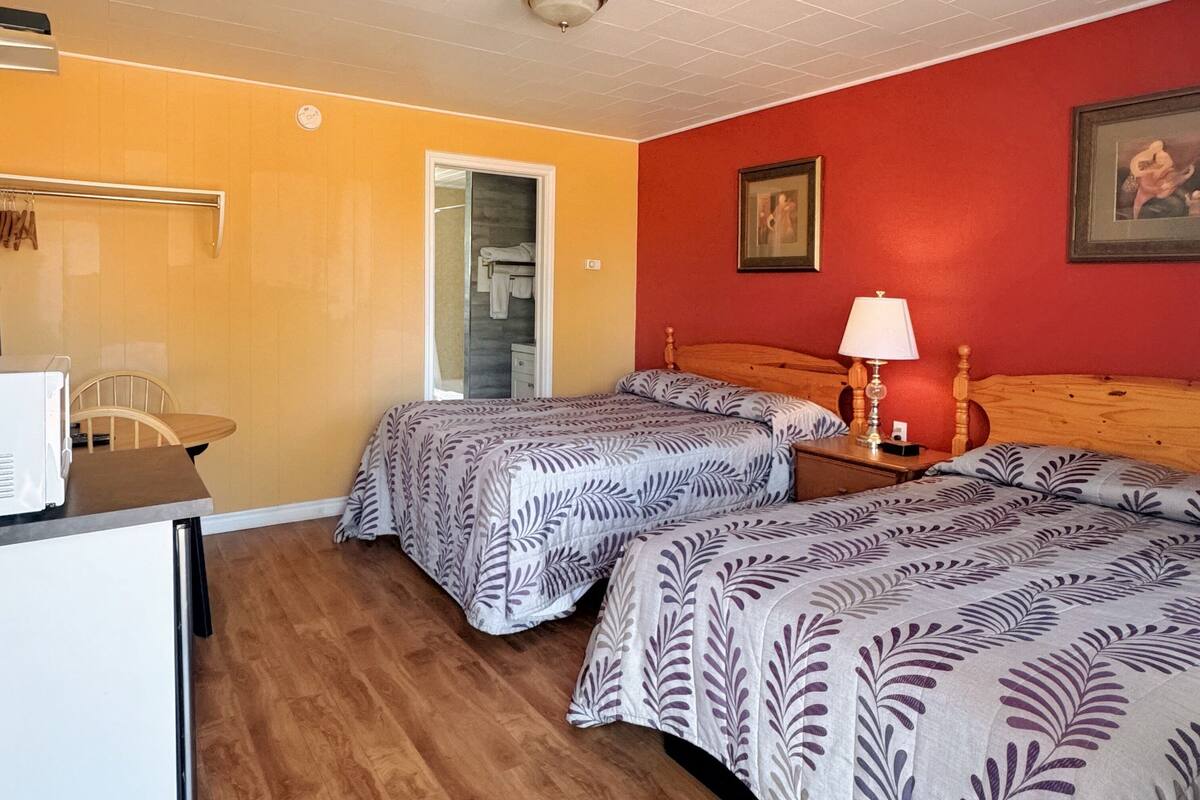 Une chambre d’hôtel avec deux lits, un bureau, une chaise et un four à micro-ondes.