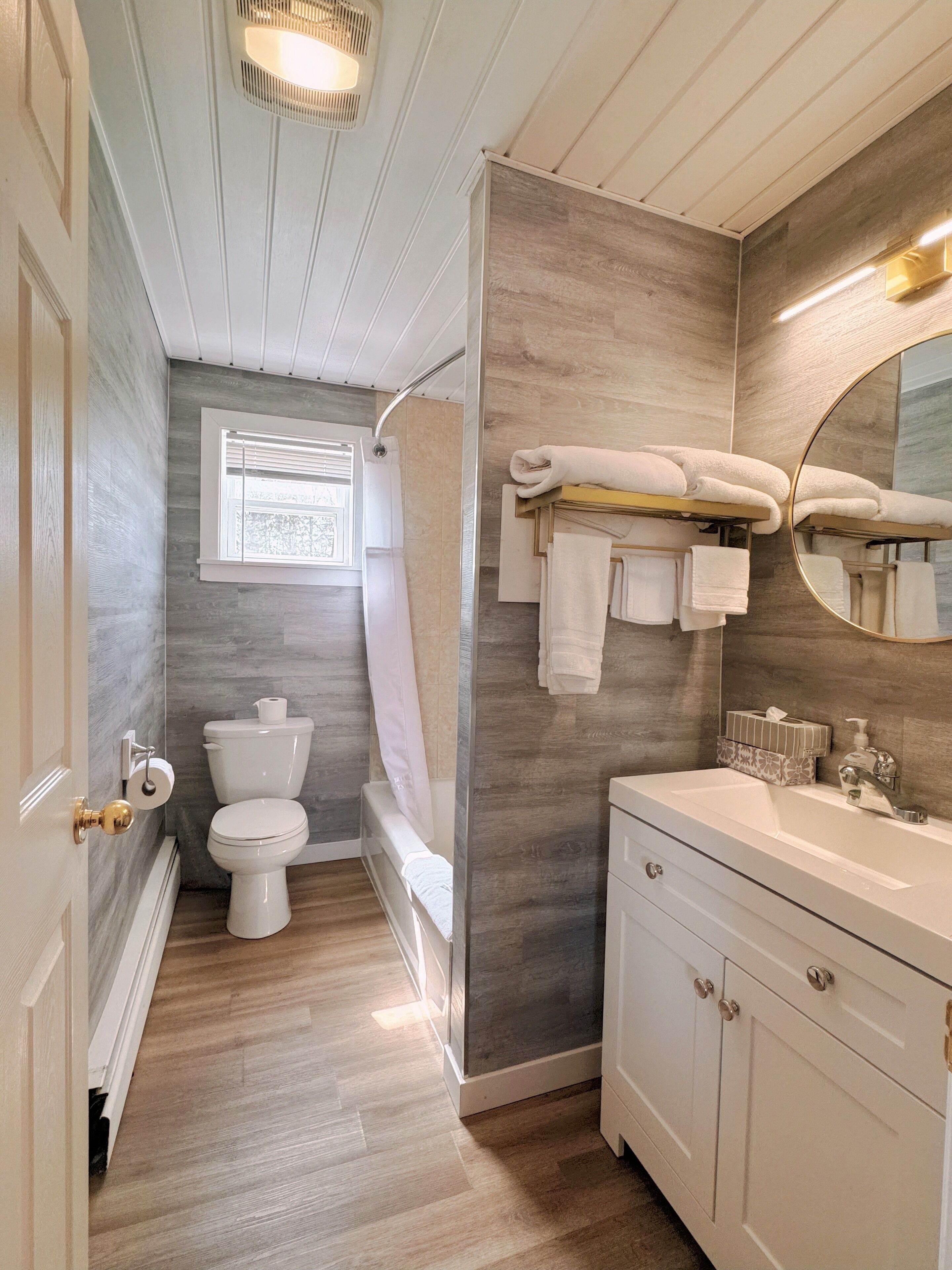 A bathroom with a toilet, shower, and sink.