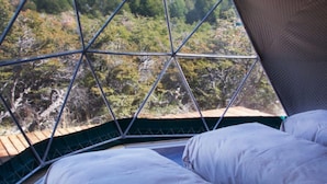 Una carpa con estructura geométrica y una cama en su interior.