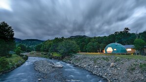 Un río serpentea a través de un paisaje rocoso, con una gran estructura de cúpula geodésica al fondo.