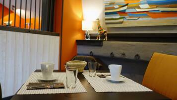 A dining area with a table set for two, featuring a white cup, a glass, a napkin, and a small basket.