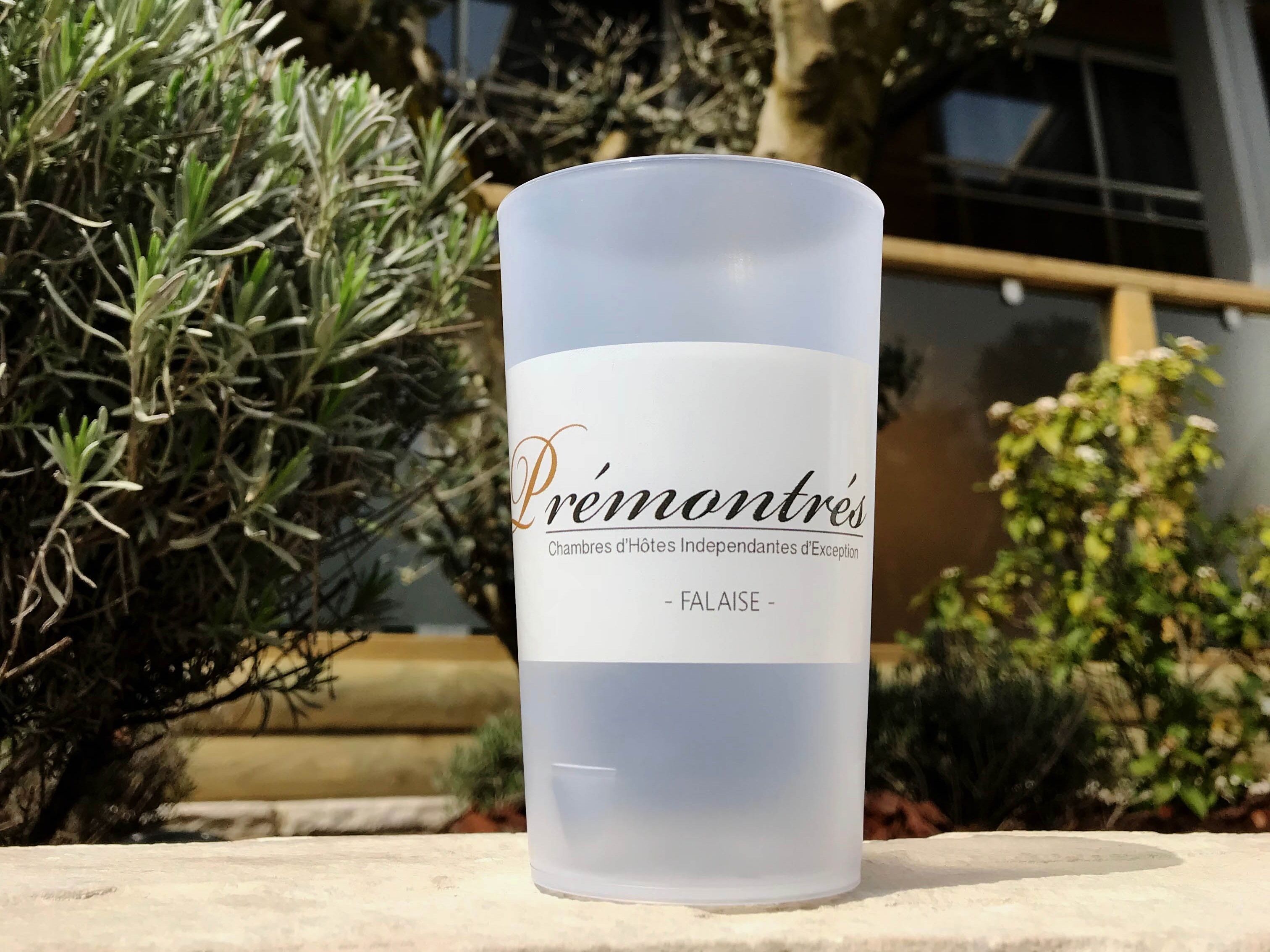 Un verre transparent, de forme cylindrique, portant une étiquette indiquant : « Chambres d’hôtes indépendantes d’exception de Prémontré – Falaise ».