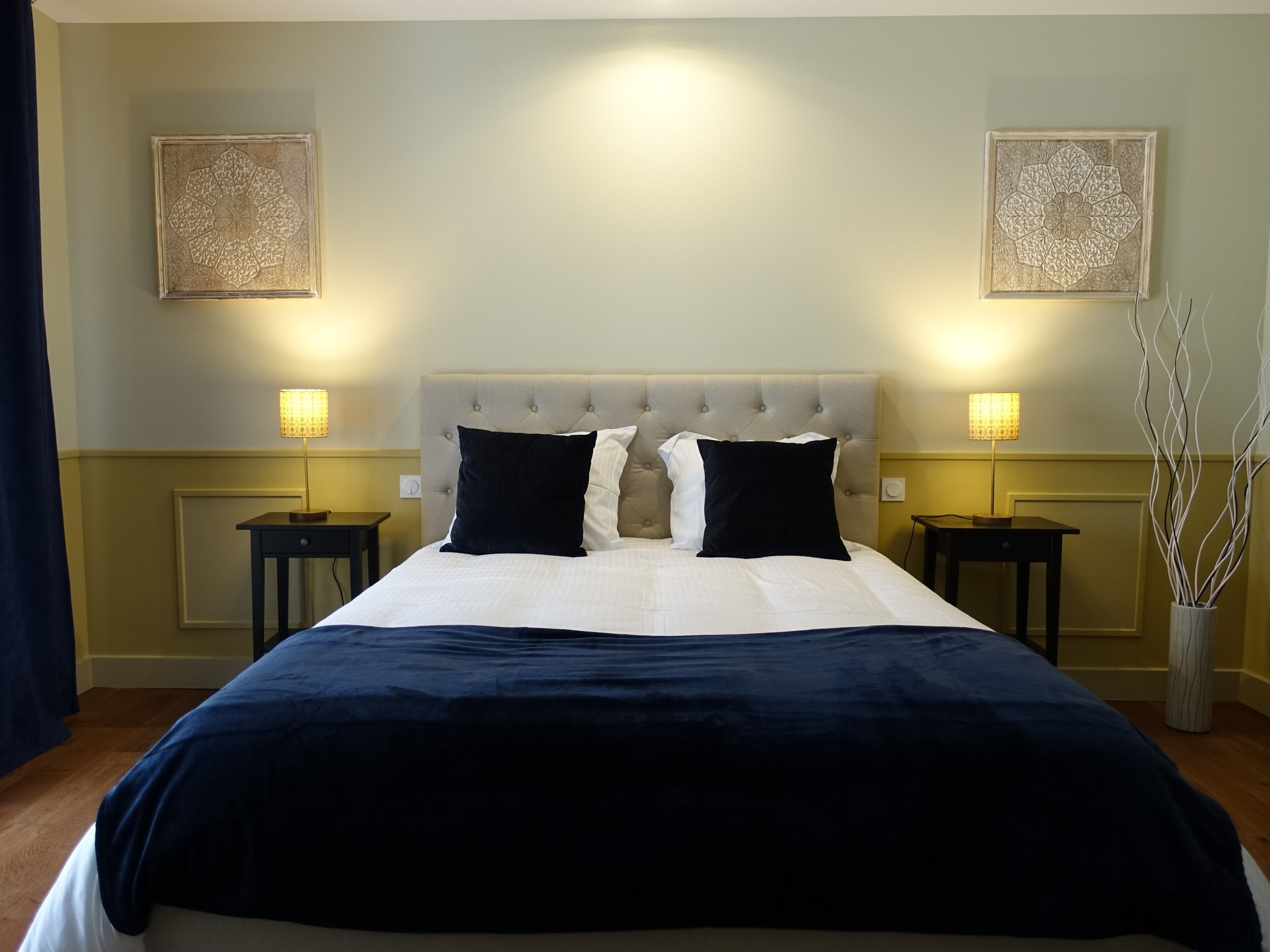 A hotel room with a large bed, two bedside tables, and two wall-mounted lamps.