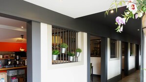 Un interior modern amb zona de cuina, plantes en testos i un passadís.