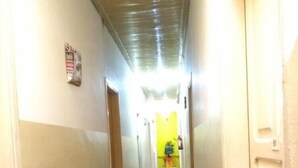 A hallway with a shiny black floor, a potted plant on the left, and a door on the right. - Hotel Triunfo (Londrina)