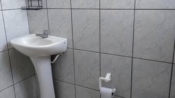 Casa de banho com lavatório branco, sanita e paredes em azulejo.