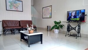 A living room with a brown leather sofa, a coffee table with flowers, a TV on a stand, and a map on the wall. - Hotel Triunfo (Londrina)