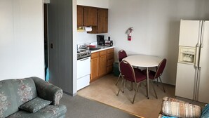 A compact living space with a kitchenette, a dining table with chairs, a sofa, and a refrigerator. - The Landing on the Wolf (Winneconne)