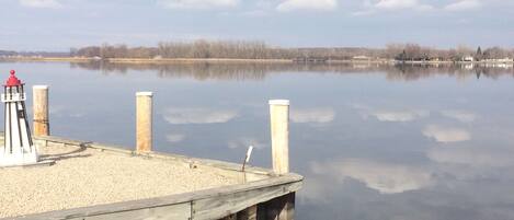 A calm lake with a wooden dock and a lighthouse.