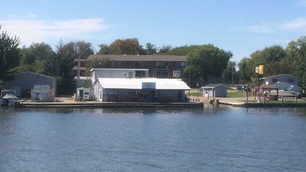 A waterfront property with a large building, a dock, and a small boat. - The Landing on the Wolf (Winneconne)