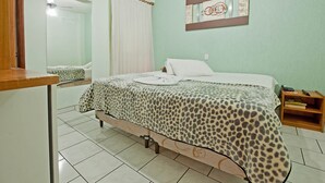 Un dormitorio con cama, mesita de noche, espejo y una obra de arte en la pared.