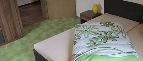 A bedroom with a bed, a nightstand, a lamp, and a door to a closet.