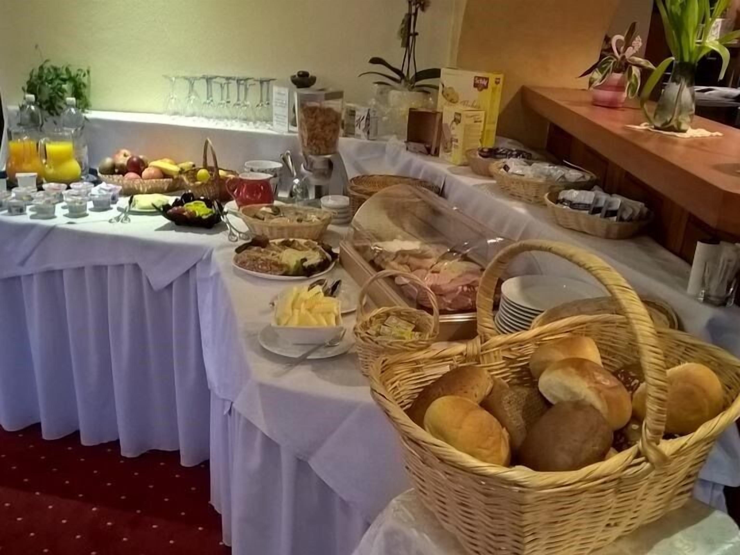 A buffet table with various food items and drinks, including fruits, bread, and a coffee maker.