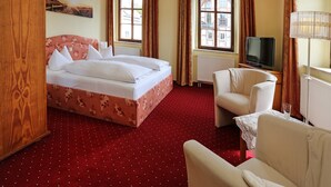 A hotel room with a bed, a TV, a chair, and a window with curtains. - Landhotel Thürmchen (Schirgiswalde-Kirschau)