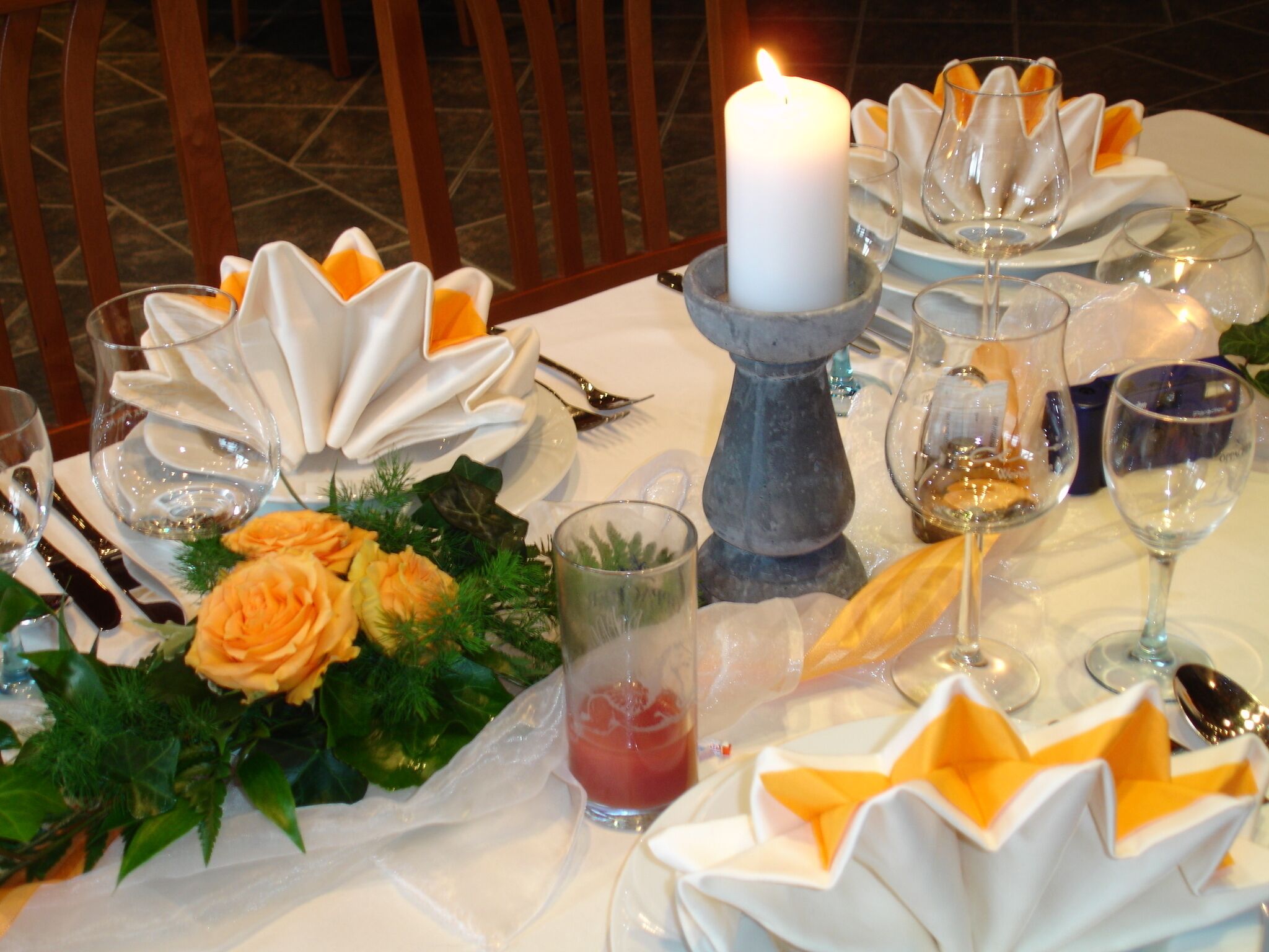 A table set for a meal with a white candle, folded napkins, and a glass of red drink.