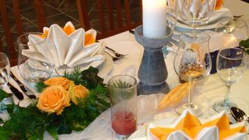 A table set for a meal with a white candle, folded napkins, and a glass of red drink.