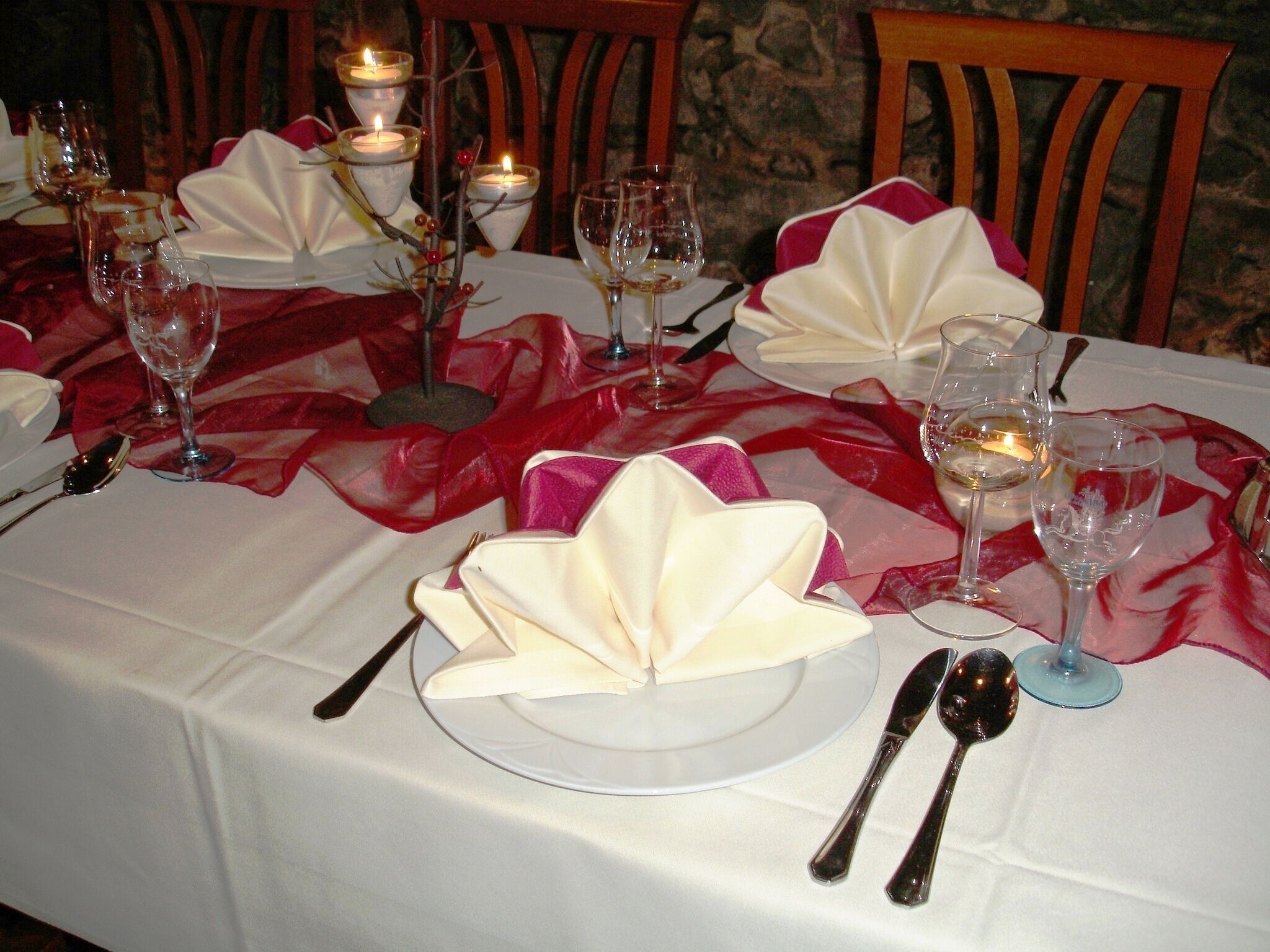 A table set for a formal dining experience with white tablecloths, red and white napkins, and candles.