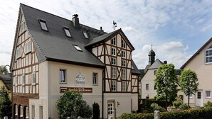 A traditional half-timbered building with a sign reading "30 Wohnzimmer Herzlich Willkommen" and a weather vane on the roof. - Landhotel Thürmchen (Schirgiswalde-Kirschau)