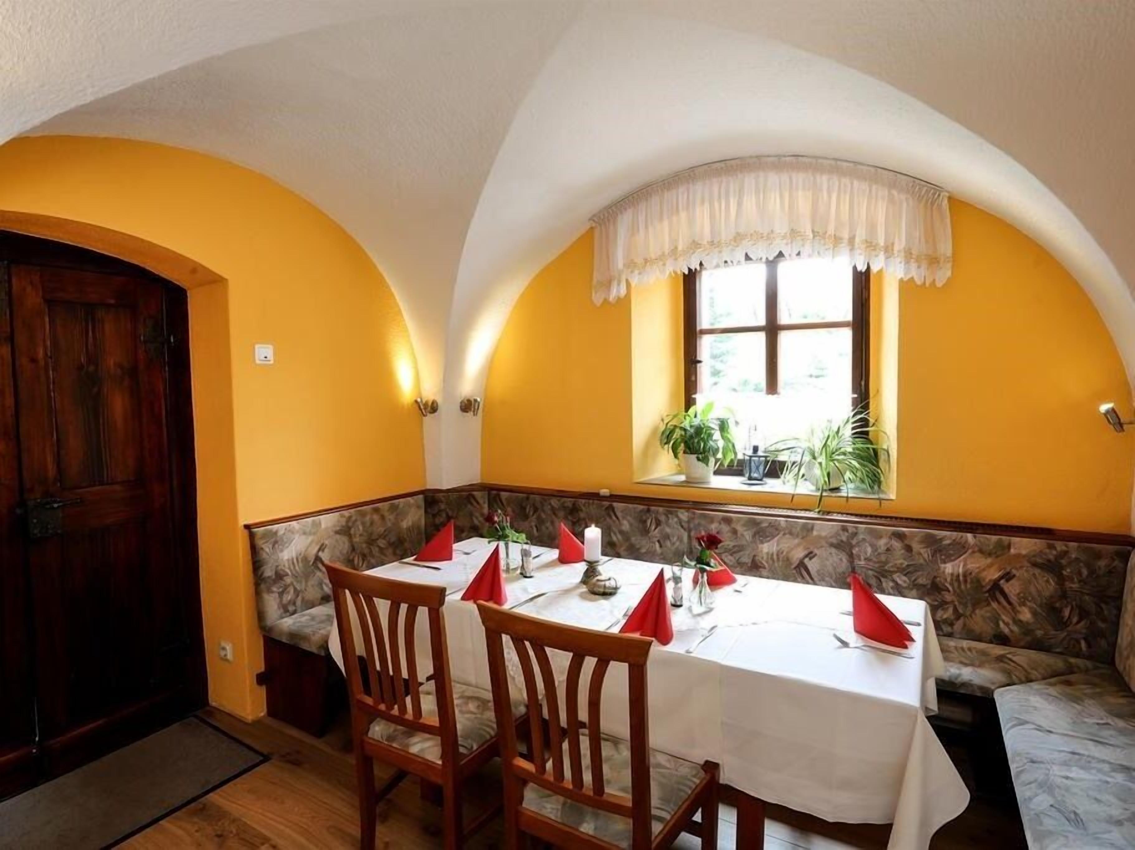 Ein Essbereich mit einem Tisch für vier Personen, einer Holztür und einem Fenster mit Pflanzen.