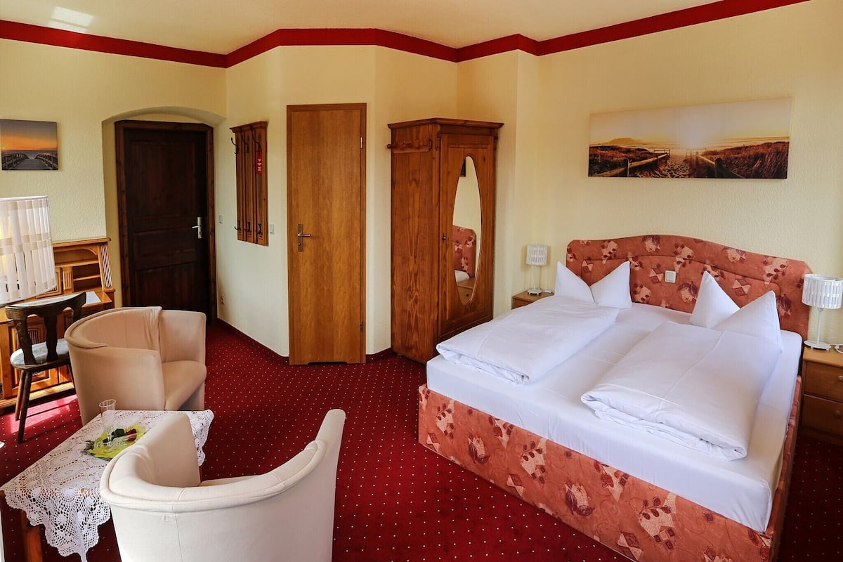 A hotel room with a bed, a chair, a desk, and a wardrobe.
