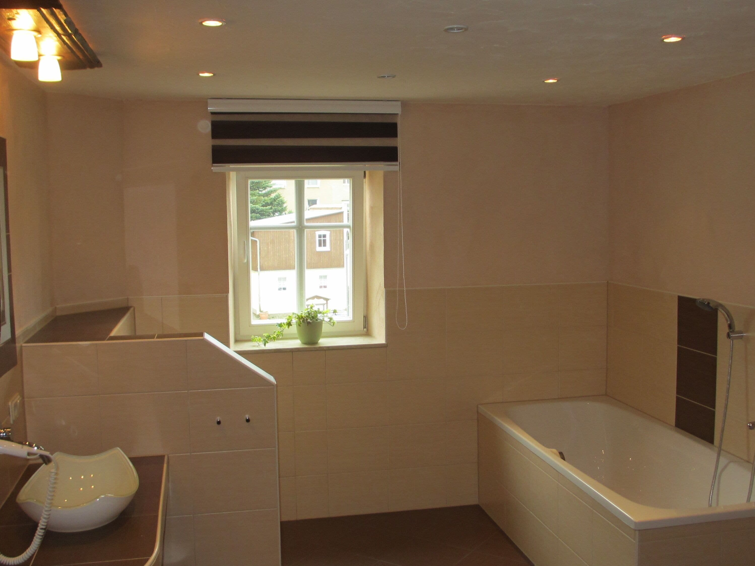 A bathroom with a bathtub, a sink, and a window with a view of buildings outside.