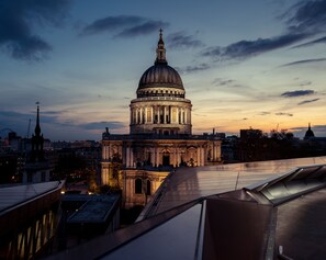 Un grand bâtiment à coupole, de style architectural classique, entouré de bâtiments modernes et sous un ciel dégagé.