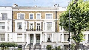 A row of terraced houses with white facades, brick detailing, and a central entrance with steps. - Kensington Apartment with terrace (London)