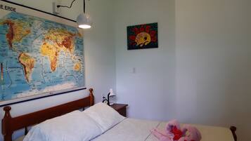 Un dormitorio con una cama, un mapa del mundo, un cuadro y una lámpara.