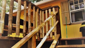 Una escalera de madera con barandilla que lleva a un edificio amarillo con una ventana.