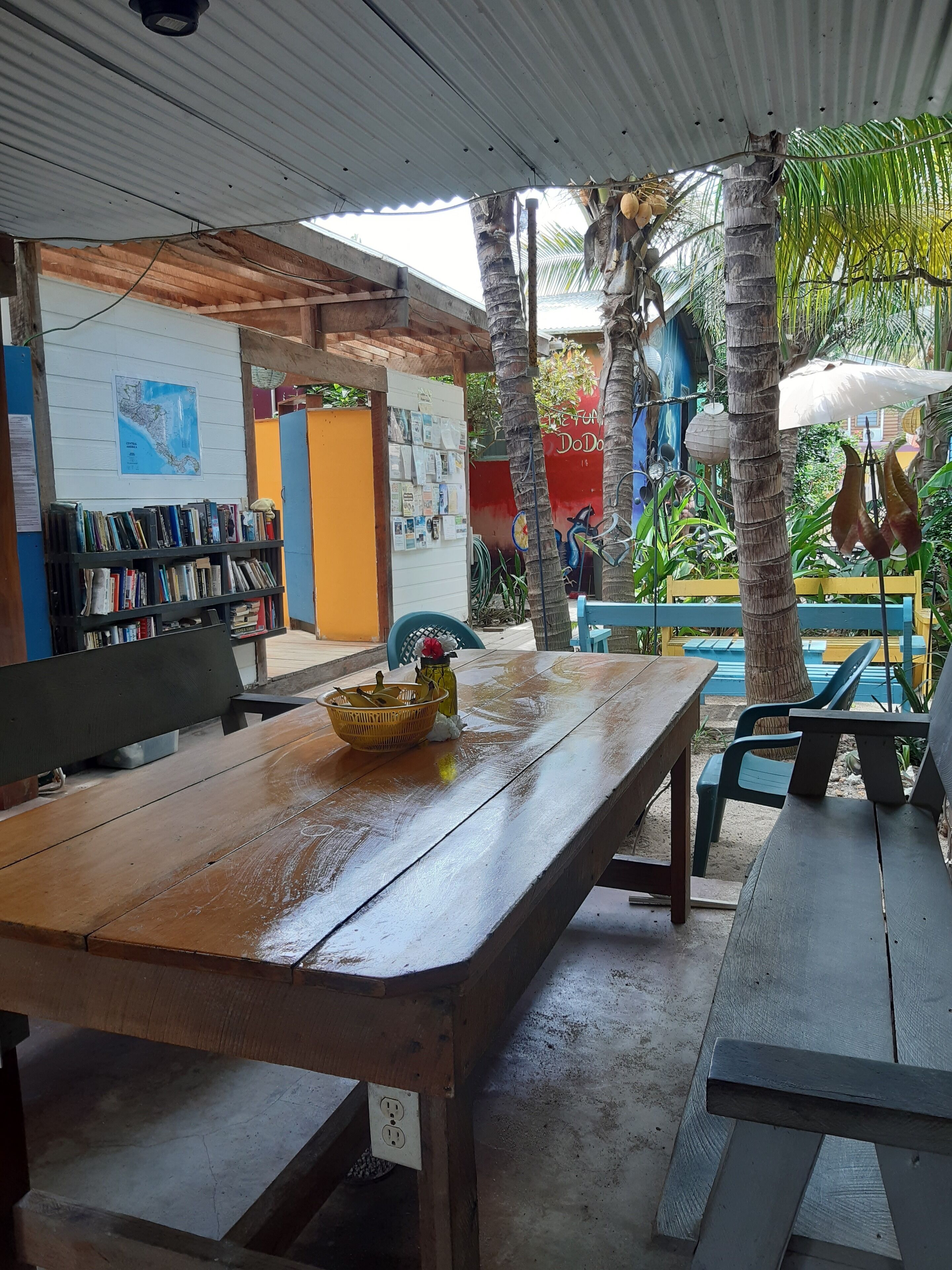Un espace extérieur aménagé avec une table en bois, des bancs et une bibliothèque.
