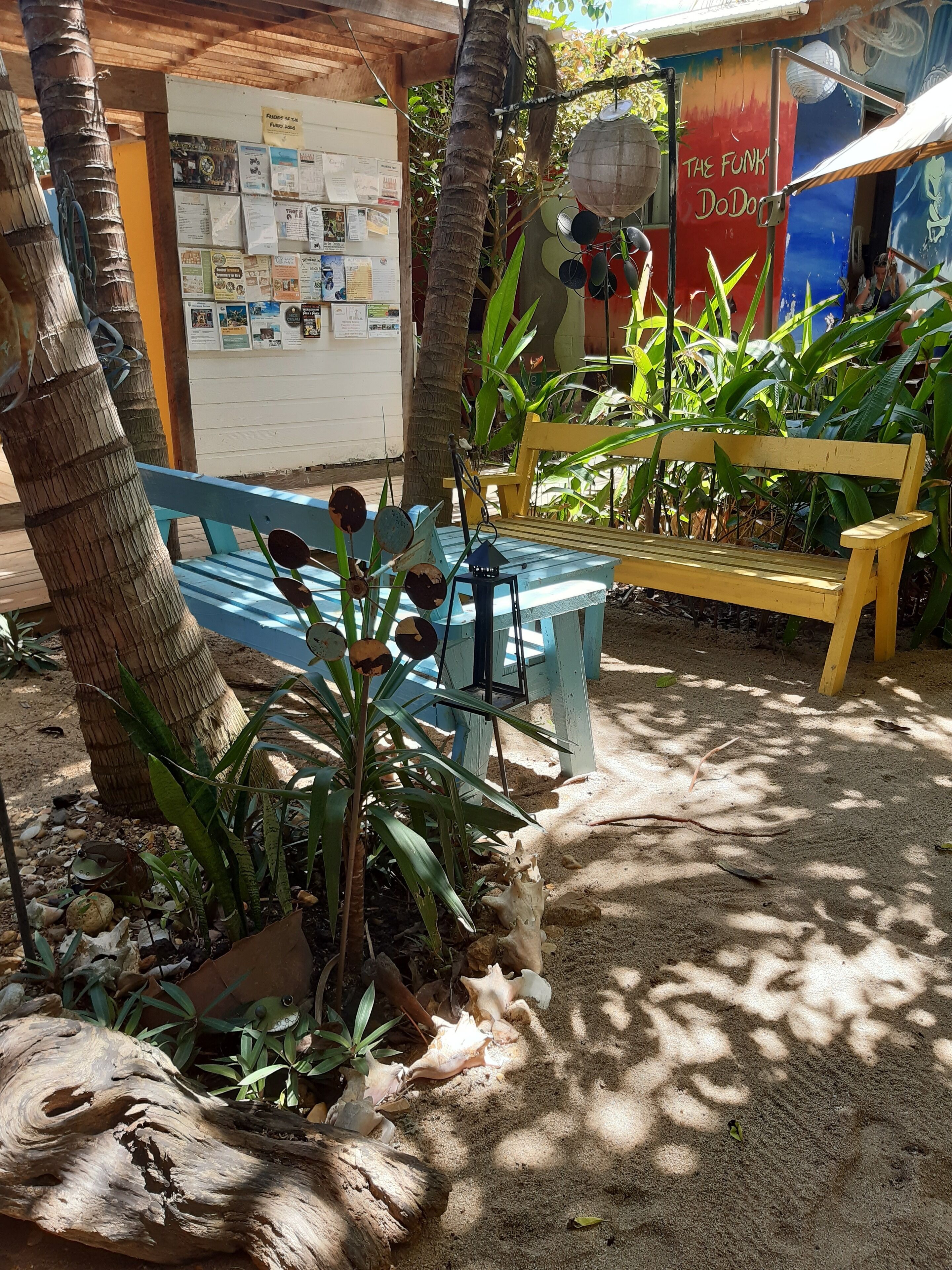 A wooden bench, a bulletin board, and a wall with a mural.