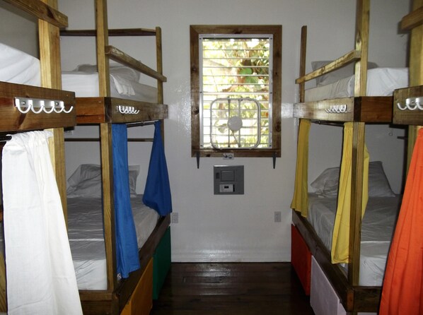 Un dormitorio con literas, una ventana con barrotes y un enchufe en la pared.