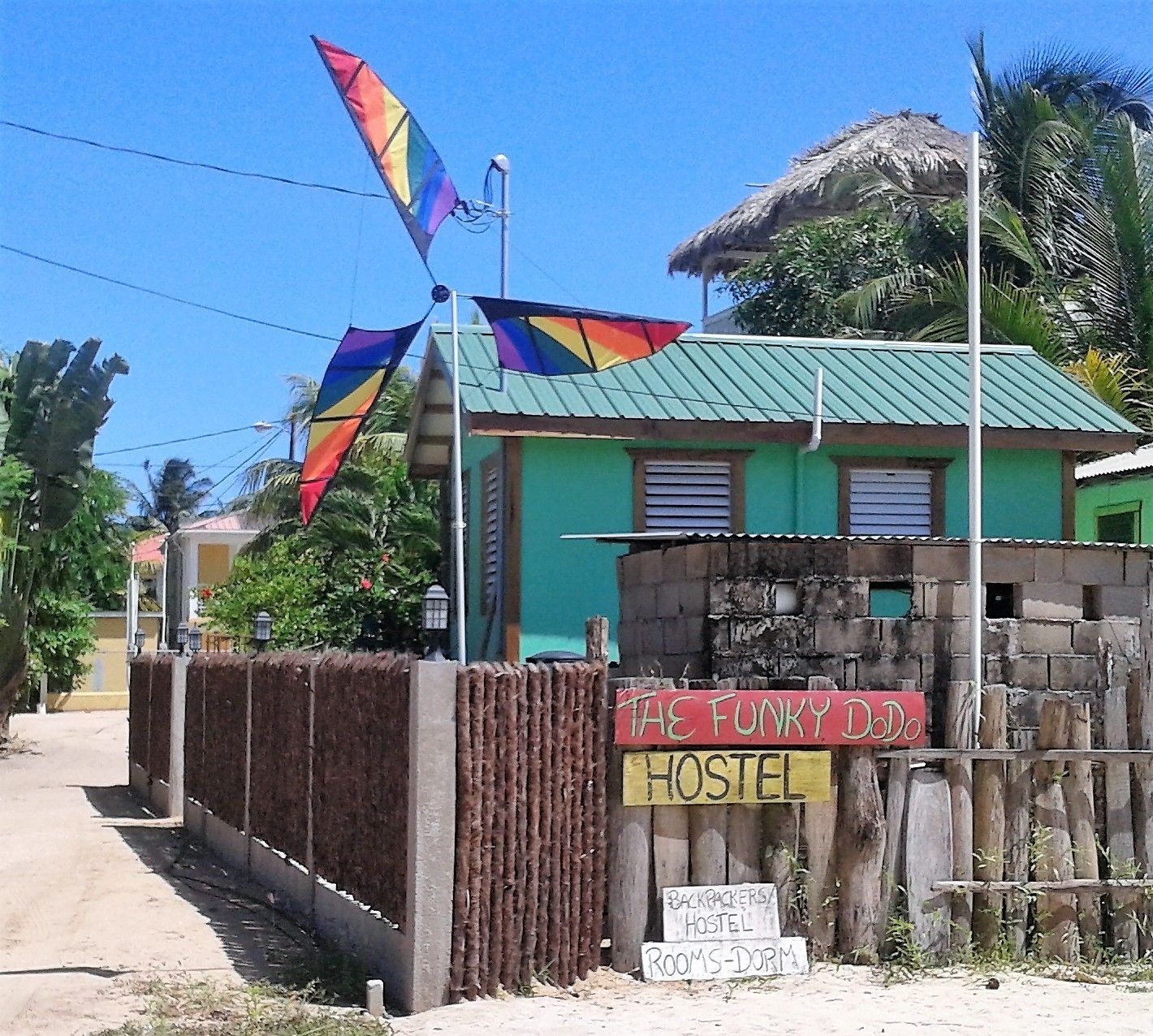A hostel with a colorful flag, a sign reading "The Funky Doo Hostel", and a sign for "Backpackers Hostel Room 5 Dorm".